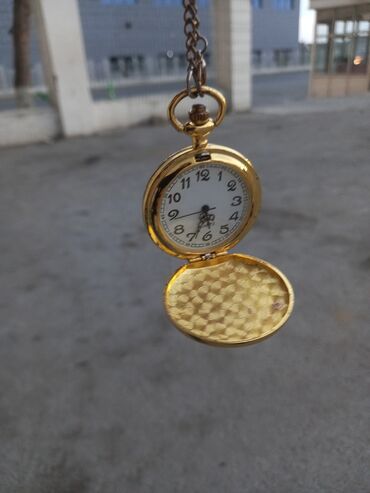 omeqa saat: Zəncirli qızılı rəngli cib saatı. Qapağı açılır və üzərində romb