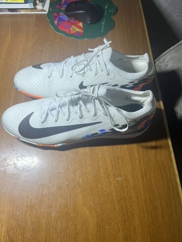Krasofkalar və idman ayaqqabıları: Ağ rəngdə olan Nike futbol ayaqqabıları. Ayaqqabıların üzərində qara