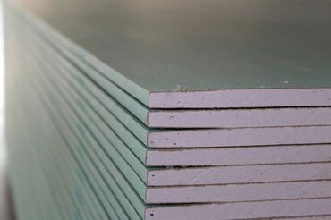 Водосточные желоба: Стопка листов гипсокартона зеленого цвета. Этот тип гипсокартона