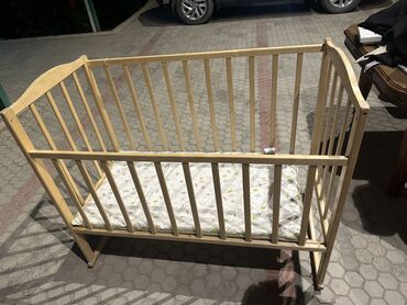 детскую коляску и кроватку: Детская кроватка из светлого дерева, предназначенная для