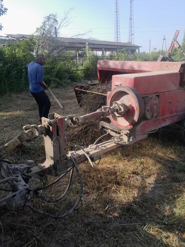 vurux masinlar: Qırmızı rəngli, qoşqu ilə hərəkət edən ot presləmə maşını. Kənd