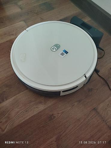 buxarli tozsoranlar: Ağıllı robot tozsoran – dairəvi, ağ korpus, aşağı profilli dizayn. Dok — 1