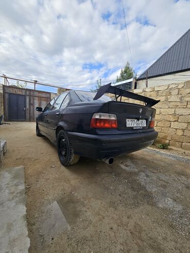 afdamabilər: Goy rəngdə olan BMW E36 sedanı satılır. Maşının arxasında böyük bir