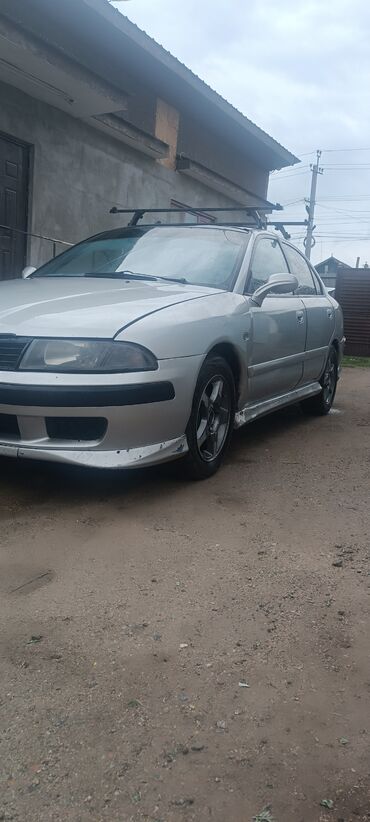 электроный скутер: Серебристый седан Mitsubishi Carisma, оборудованный черным багажником
