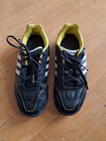 Krasofkalar və idman ayaqqabıları: Qara rəngli, ağ zolaqlı Adidas krossovkaları. İçərisi sarı rəngdədir