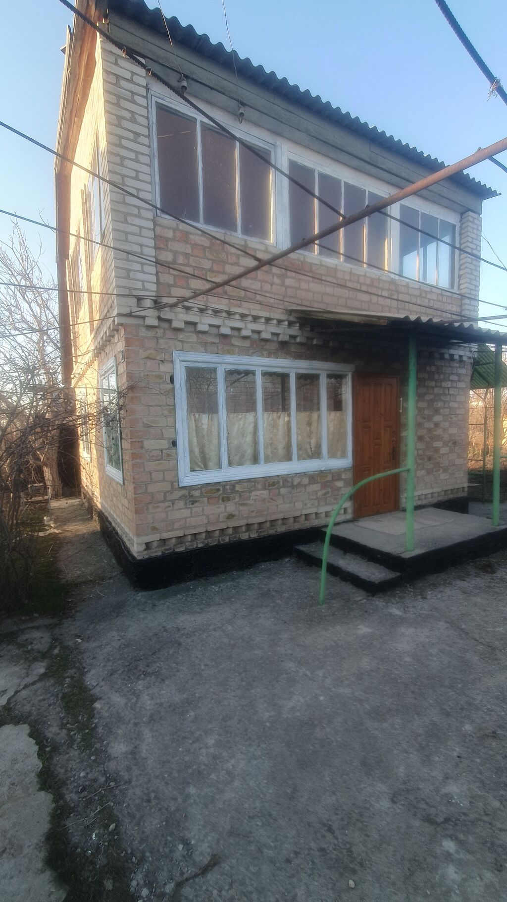 Двухэтажный кирпичный дом с застекленной верандой и навесом у входа: фото 1